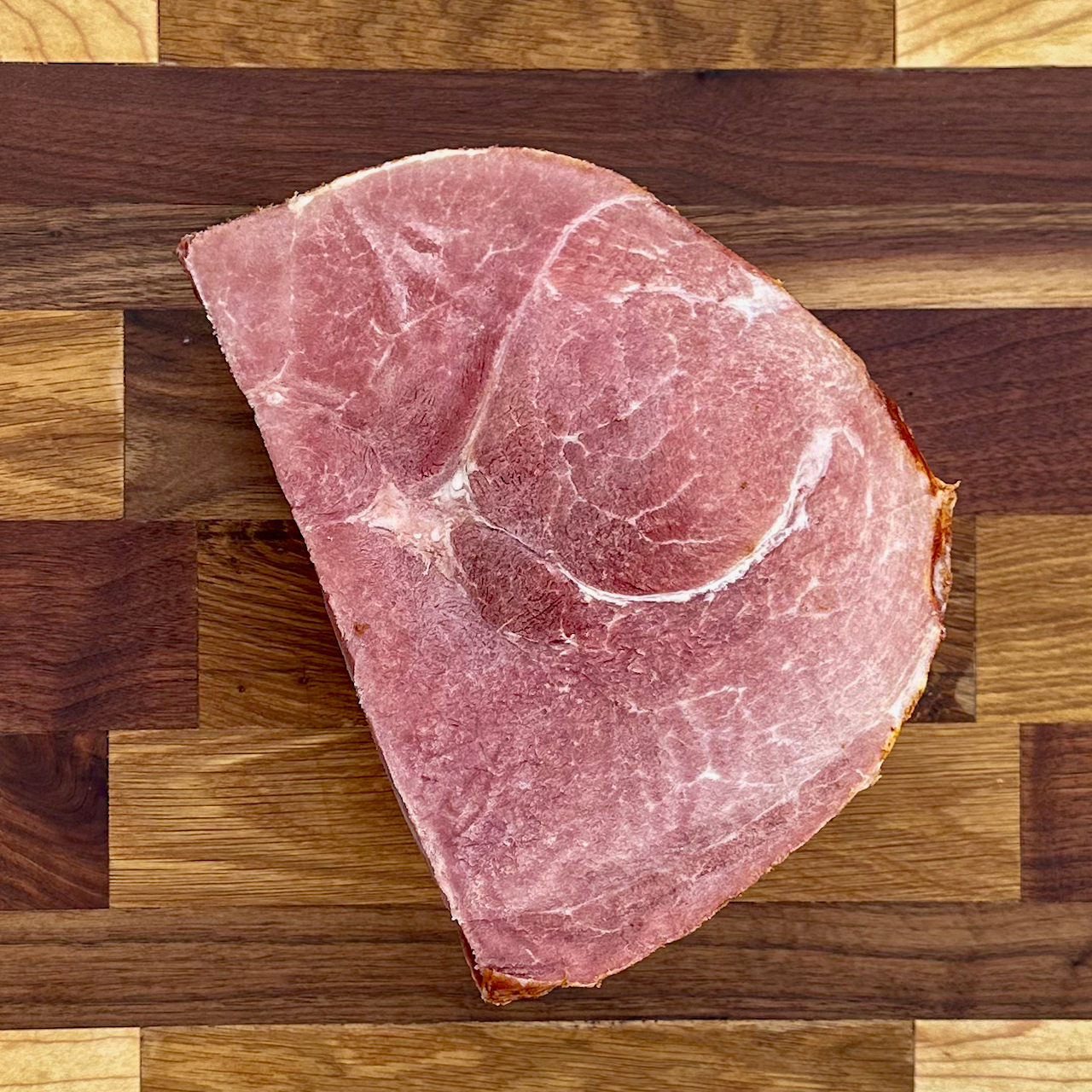 A quarter ham from Fertile Acreage Farms on a cutting board showcasing the marbling of heritage ham.