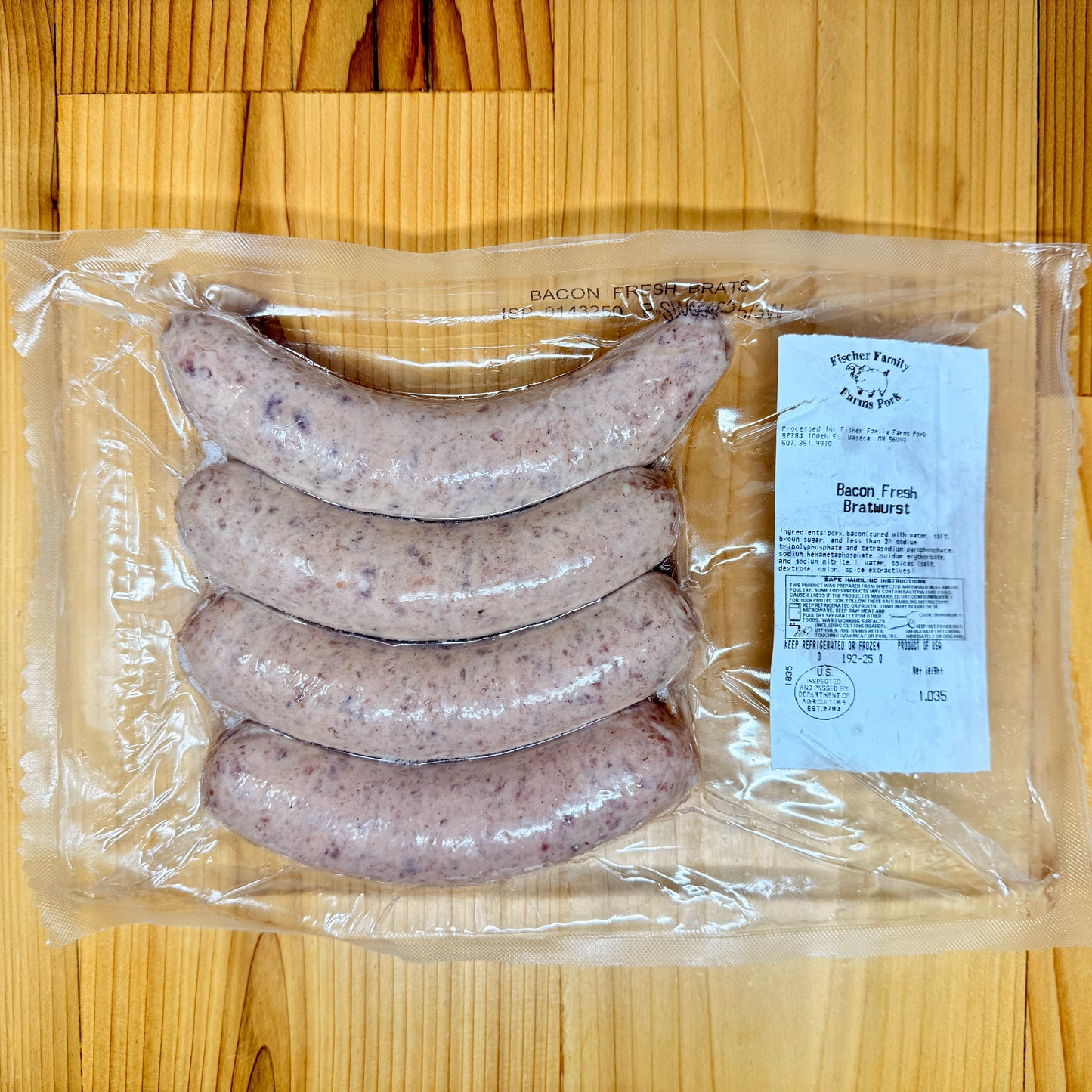 A package of 4 Bacon Fresh Brats from Fischer Family Farms on a wooden surface