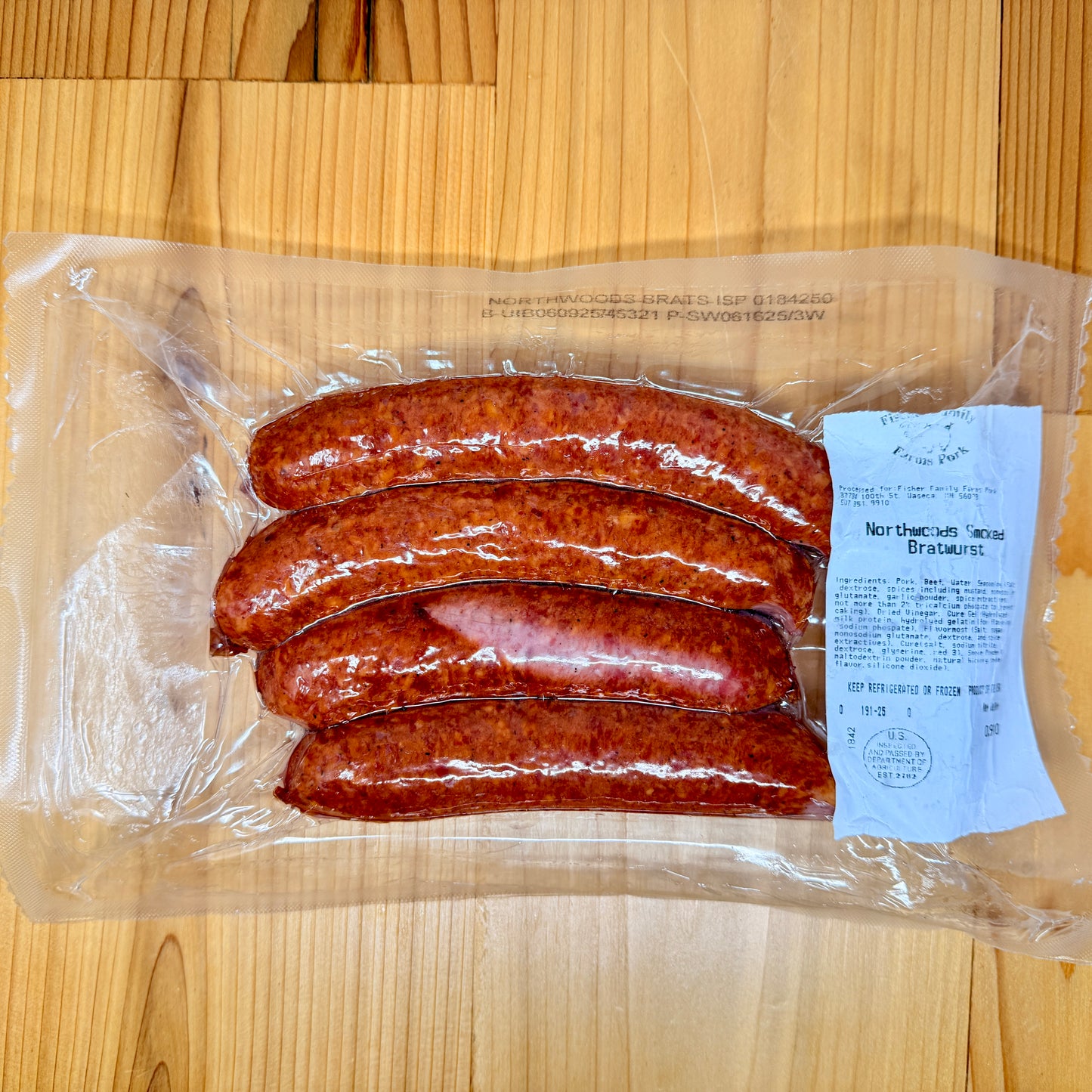 A package of 4 Northwoods Smoked Brats from Fischer Family Farms on a wooden surface