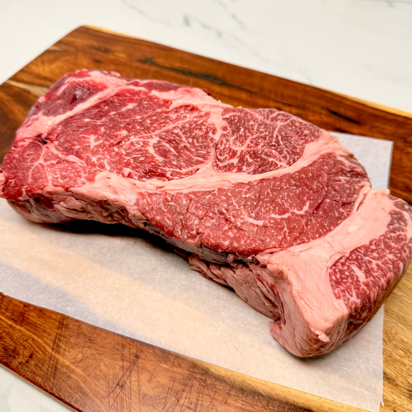 An American Wagyu Chuck Roast from Verlinde Farms on a wooden cutting board with white paper underneath