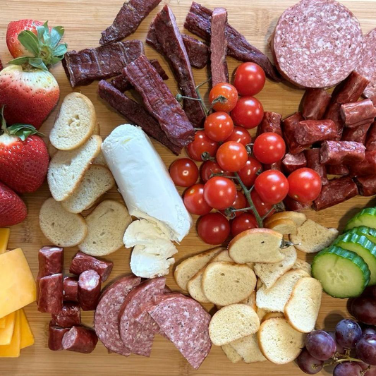 Assorted meats, cheeses, crackers, and vegetables on a wooden board
