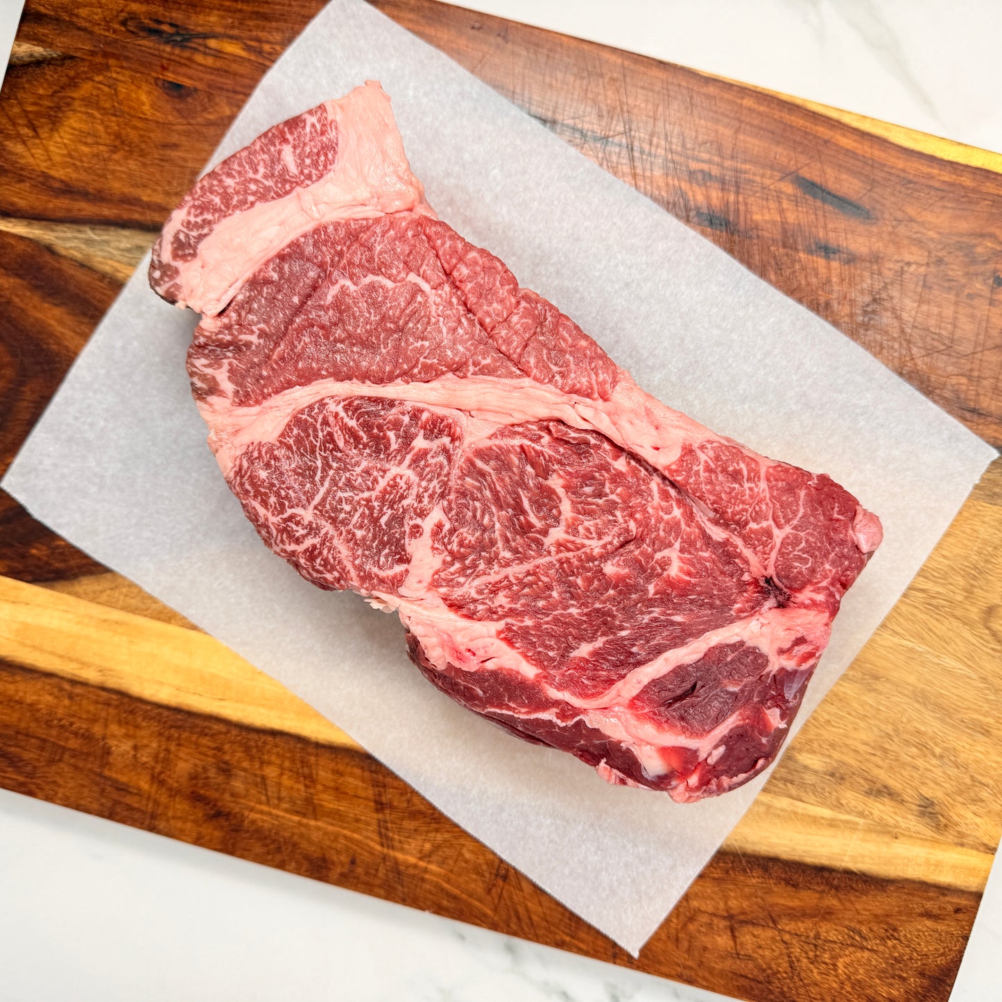 An American Wagyu Chuck Roast from Verlinde Farms on a wooden cutting board with white paper underneath