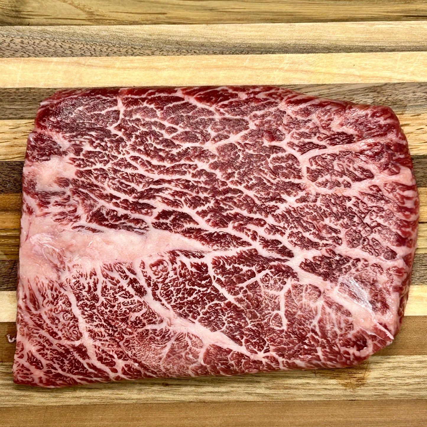 A flat iron steak from Verlinde Farms on a cutting board, showcasing the incredible marbling of American Wagyu beef.