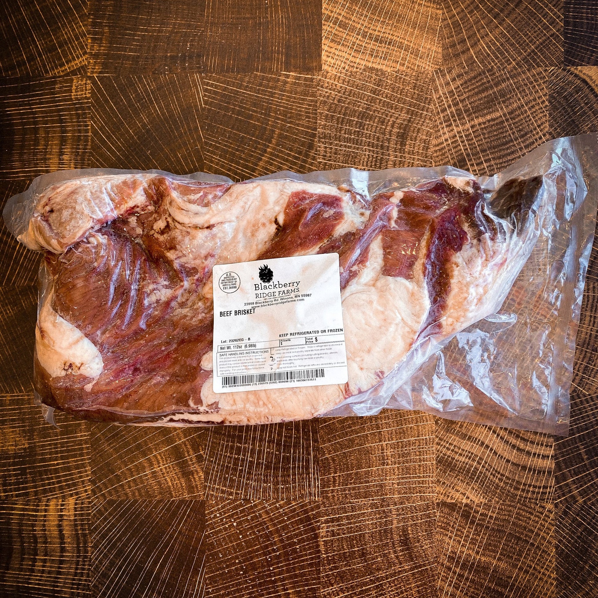 An all-natural, grass-fed beef brisket from blackberry ridge farms laying on a butcher block in it's packaging.
