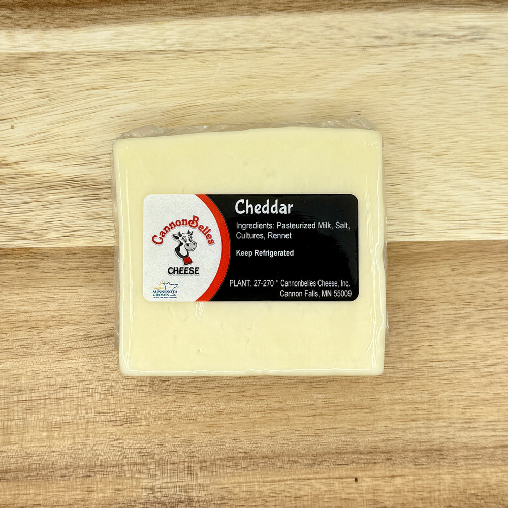 Contents of the CannonBelles Cheese Classic Cheese Box, including white cheddar, Tuscan cheddar, gouda, and Colby cheeses.