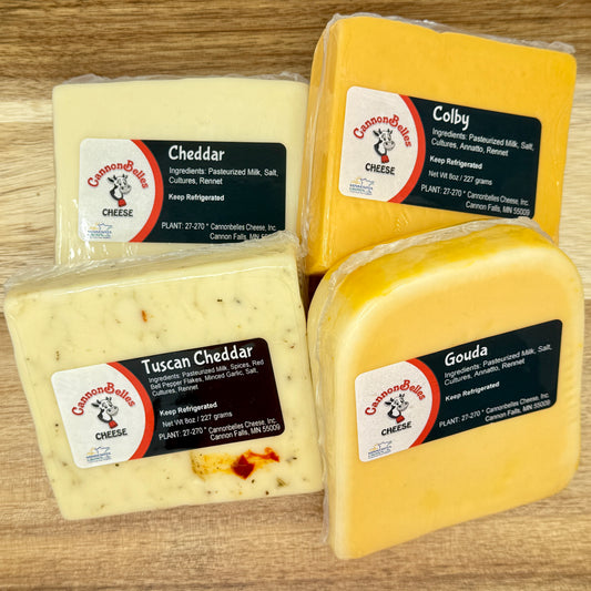 Contents of the CannonBelles Cheese Classic Cheese Box, including white cheddar, Tuscan cheddar, gouda, and Colby cheeses.