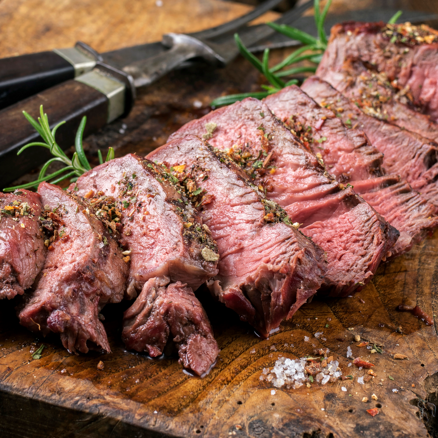 Sliced beef with herbs on a wooden cutting board