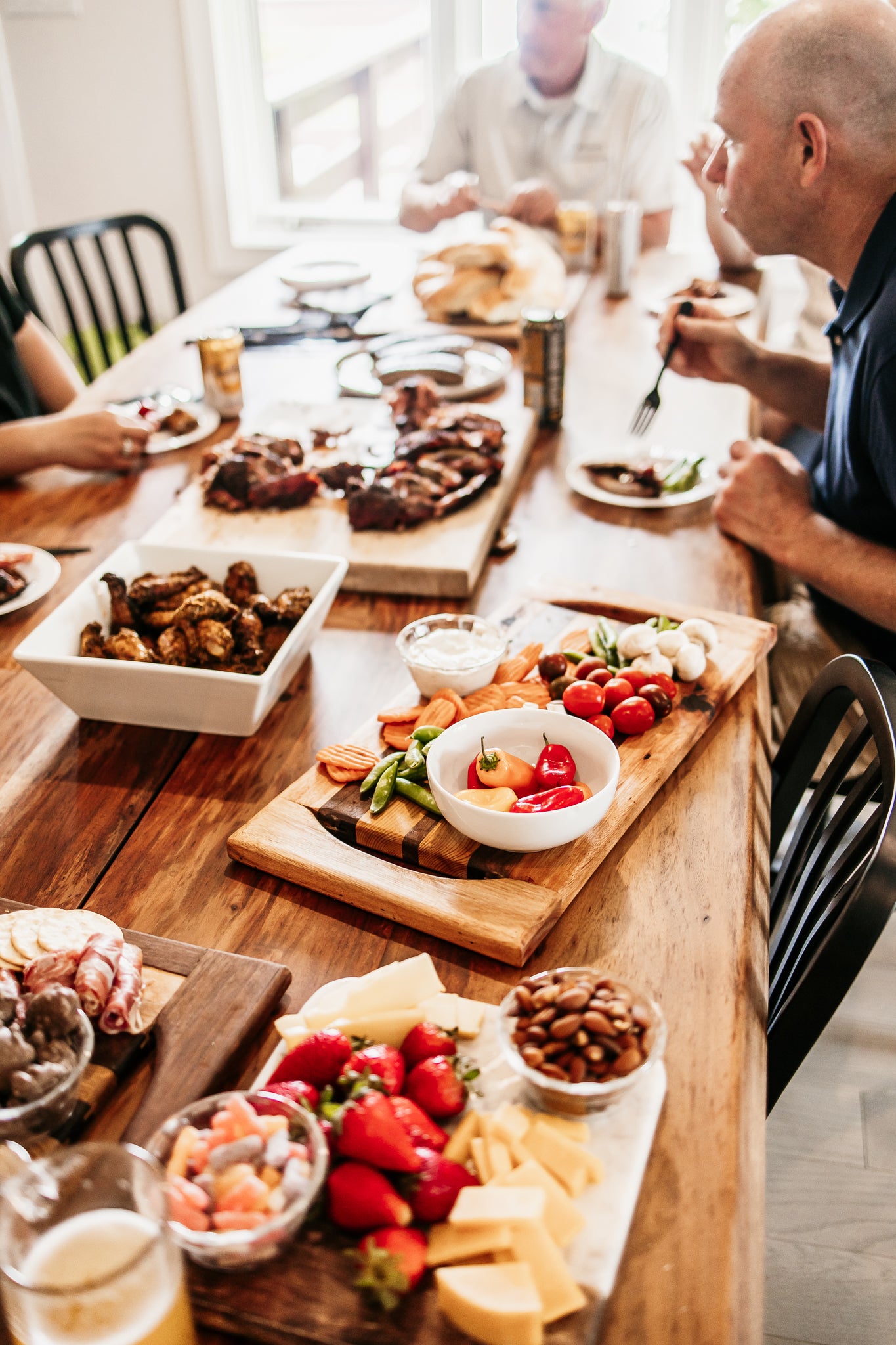 People sitting at a wooden dining table with food and drinks