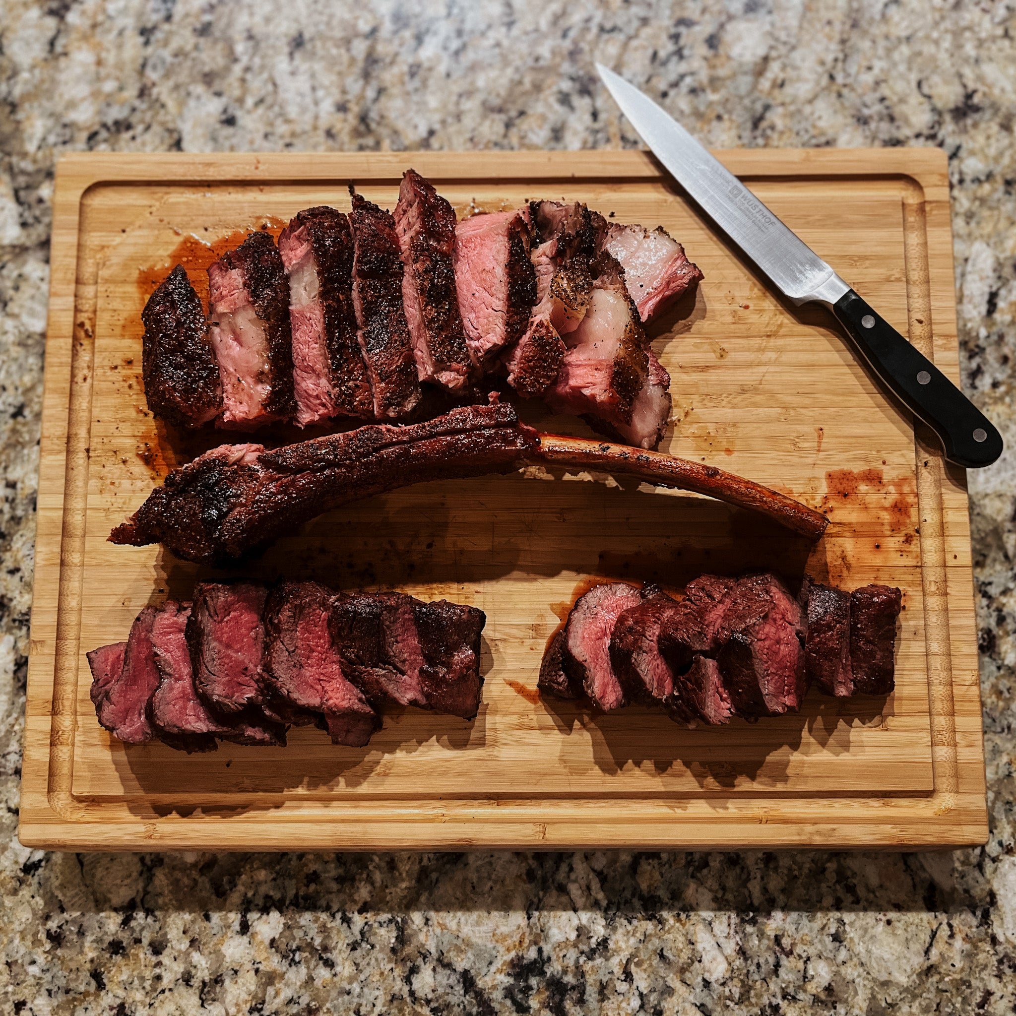 A perfectly cooked beef tomahawk, sliced and arranged on a cutting board. 