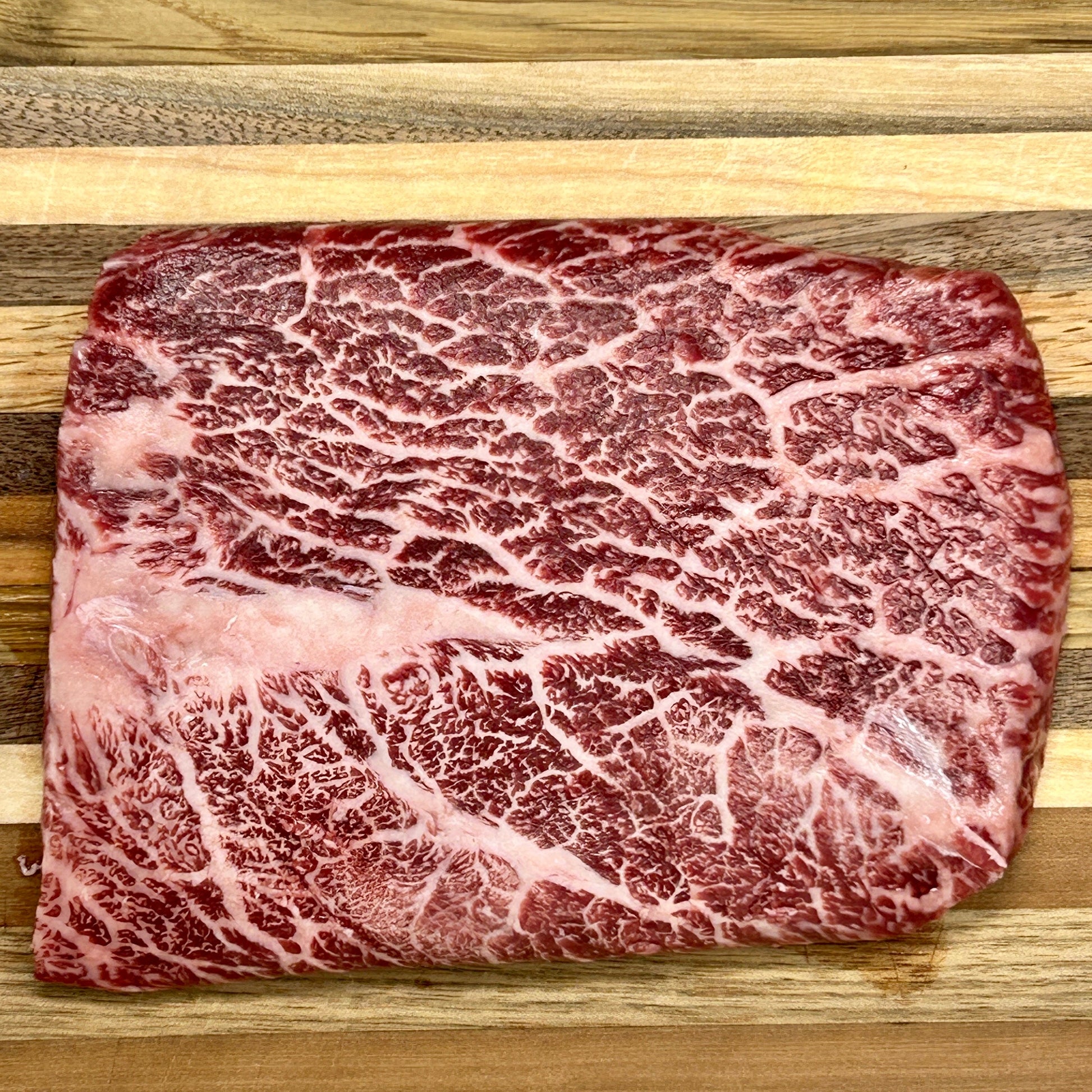 A flat iron steak from Verlinde Farms on a cutting board, showcasing the incredible marbling of American Wagyu beef.