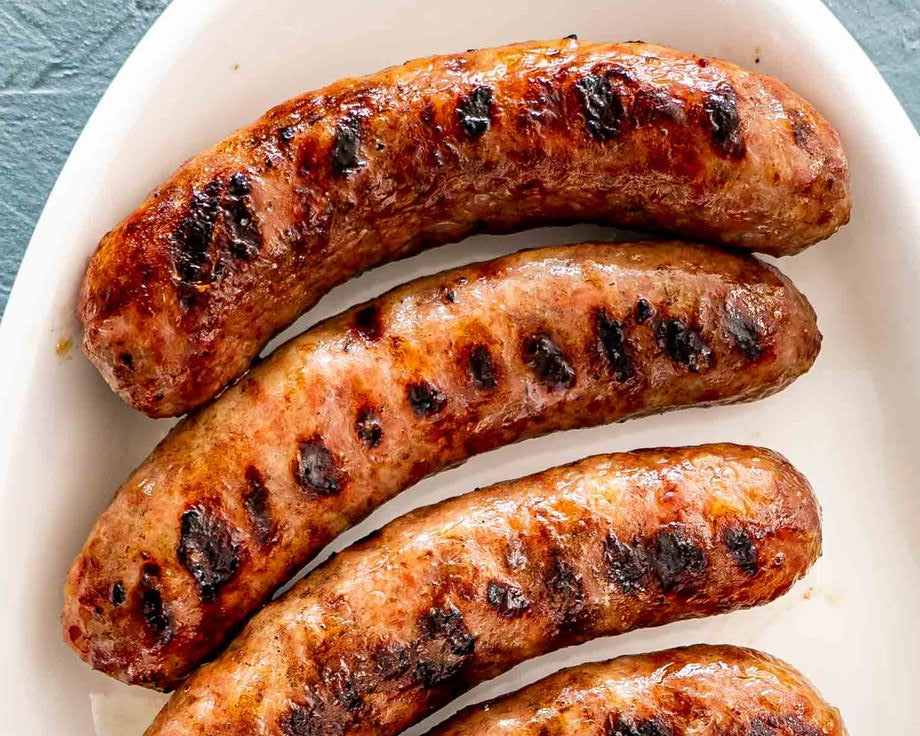 Grilled brats on a white plate with a blue surface underneath